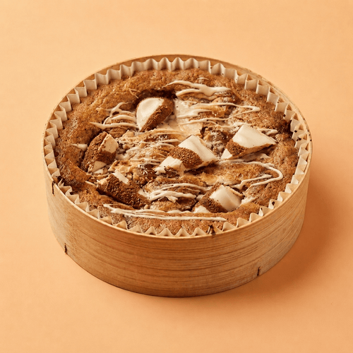 Maxi cookie Kinder Bueno White et pépites de chocolat au lait, fait maison, servi dans un pot en bambou, garni de morceaux fondants